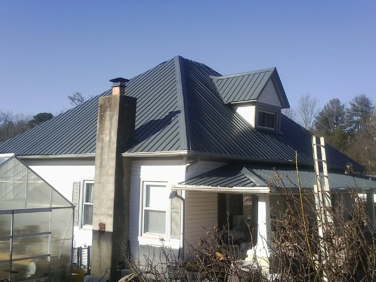 Dark blue standing seam metal roof on a white farmhouse with dormer — Slate & Tile Roof Repair by Roofing Brothers in Powell Butte