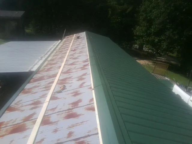 Old rusted panels beside newly installed green metal roofing — Wind Damage Roof Repair by Roofing Brothers in Powell Butte