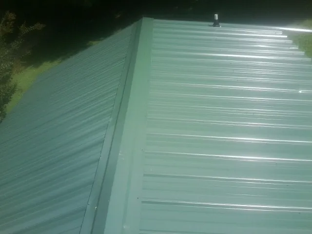 New green metal panels meeting at the ridge of a roof — Flat Roof Repair work by our crew in Powell Butte