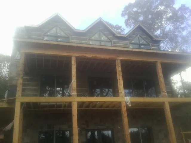 Dormers and porch framing on a large log home under construction — Roof Coating work by our crew in Powell Butte