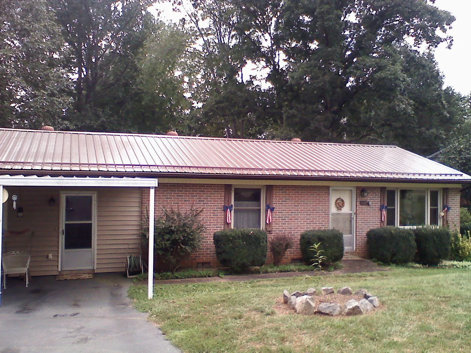 Bronze metal roof and carport on a brick ranch home — Roof Repair work by our crew in Powell Butte