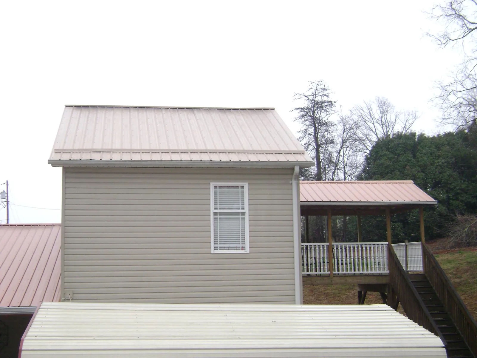 Tan metal roofs on a two story addition and attached porch, from a Roof Replacement job in Powell Butte