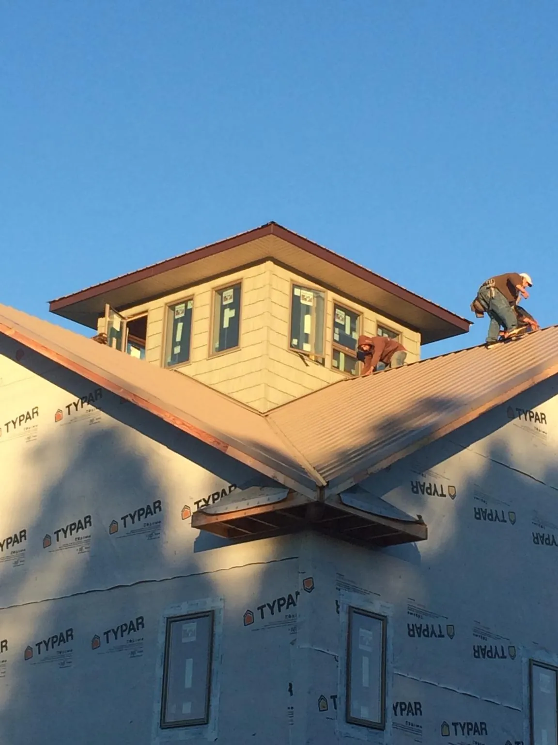 Roofers working around a rooftop cupola on a new metal roof at sunset — Roof Waterproofing in Powell Butte by Roofing Brothers